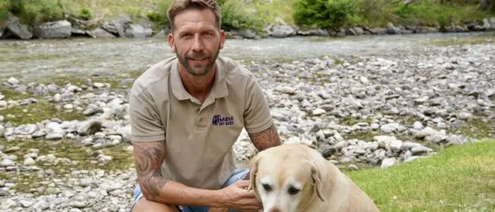 Ein Mann mit seinem Hund vor einem Fluss