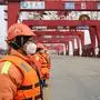 This photo taken on February 4, 2020 shows Chinese employees wearing protective facemasks working at a port in Qingdao in China's eastern Shandong province. - More Chinese cities hunkered down by fencing off streets and telling millions of people to stay home as the death toll from the new coronavirus soared to nearly 500 on February 5. (Photo by STR / AFP) / China OUT