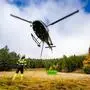 Ein Hubschrauber landet auf einer herbstlichen Waldlichtung | Der Hubschrauber hat die „Big Bags“ aus dem Steilhang der Roten Wand ausgeflogen und zur fachgerechten Entsorgung ins Tal gebracht, alles unter Aufsicht der Bergrettung