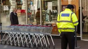  Security officer outside a Winchester supermarket. Allowing only one customer to enter at a time during Coronavirus epidemic, Winchester, Hampshire, England, UK. 65197_02_4421_027