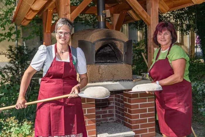 Landesbäuerin Viktoria Brandner und Verkostungschefin Eva Lipp vor dem "Einschießen", dem Hineingeben des ungebackenen Brotes in den Holzbackofen. Zum Testen der Temperatur wird vorher eine Handvoll Mehl in den Ofen gestreut. Wird dieses sehr schnell dunkel, ist der Ofen noch zu heiß.