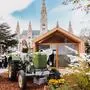 Auf dem Foto sieht man eine blonde Frau im Dirndl auf einem grünen Oldtimer-Traktor vor dem Wiener Rathaus | Auch heuer präsentieren sich wieder zahlreiche südweststeirische Betriebe am Wiener Rathausplatz