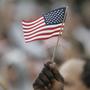 Sujetbild: Die Flagge der USA in der Hand einer dunkelhäutigen Person