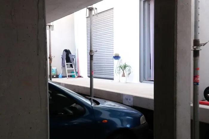 ...Bewohner im Erdgeschoß schauen in eine Betonwand und Autoauspuffrohre.