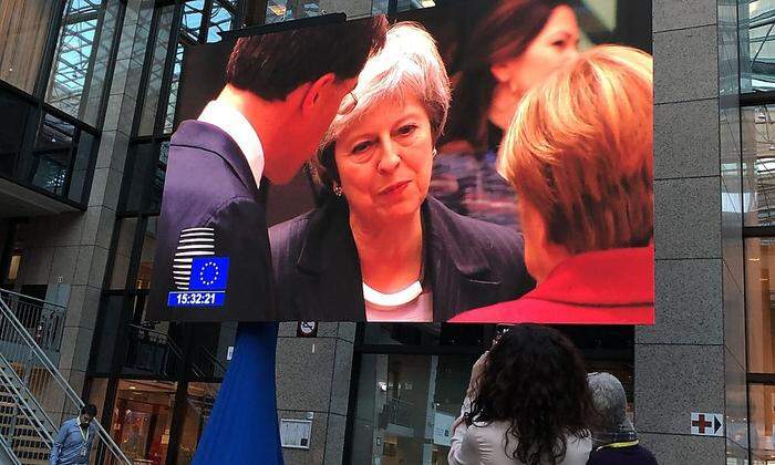 Theresa May (auf einem Großbildschirm beim Dezember-Gipfel im Gespräch mit Mark Rutte und Angela Merkel): Der Brexit wird immer verworrener