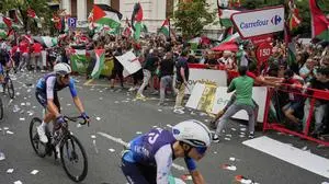 Riders of the Israel Premier Tech team compete as people holding Palestinian flags try to disrupt the eleventh stage of the Spanish Vuelta cycling race, from Bilbao to Bilbao, Spain, Wednesday, Sept. 3, 2025. (AP Photo/Miguel Oses)