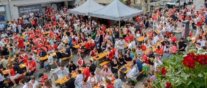 Zahlreiche Besucher verfolgen in einer Innenstadt ein Fußballspiel
