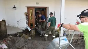 Um die völlig verschlammten Häuser zu befreien, bilden die Helfer Eimerketten