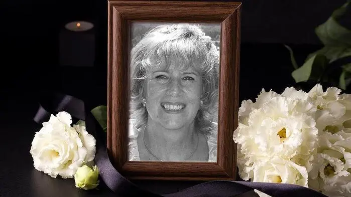 Ein Foto von einer lächelnden Frau in einem Bilderrahmen, der von weißen Blumen gesäumt ist