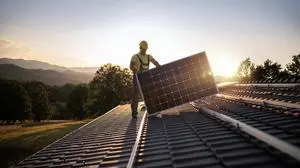 Shot Of Professional Workers Installing Solar Panels On A Roof At Sunset.