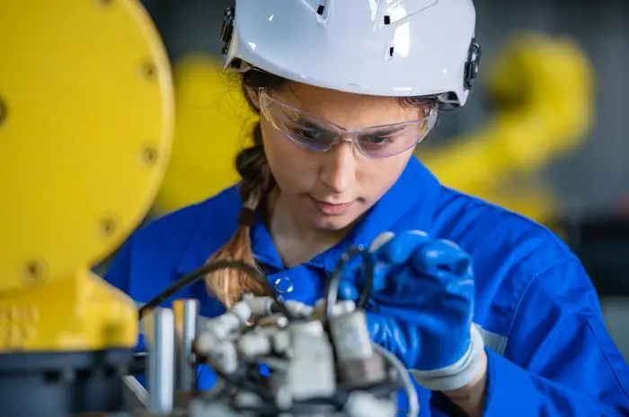 woman engineer in uniform helmet inspection check control heavy machine robot arm construction installation in industrial factory. technician worker check for repair maintenance electronic operation
