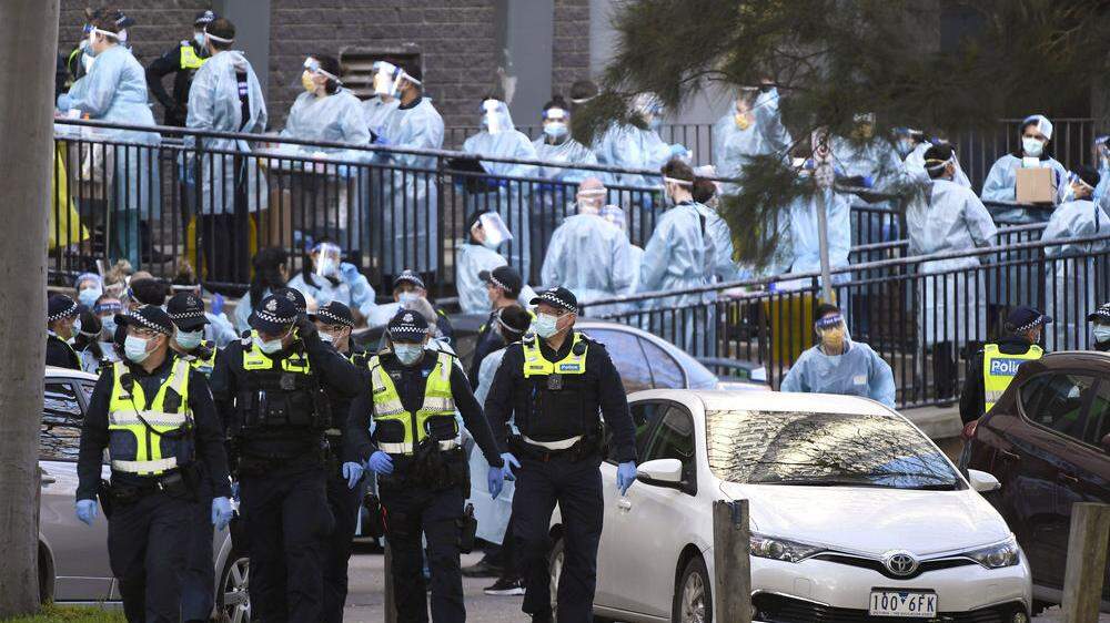 Testpersonal und Polizei in Melbourne vor einem Häuserkomplex der zur Gänze unter Quarantäne gestellt wurde.