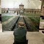 Ein ehemaliges Holocaust-Opfer vor einem Foto des KZ Auschwitz 