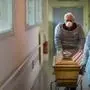 Employees of the Lantz funeral company, wearing face masks as protective measures, pull the coffin of a victim of the COVID-19 at an hospital in Mulhouse, eastern France, on April 5, 2020 during a strict lockdown in France to stop the spread of COVID-19 (novel coronavirus). (Photo by SEBASTIEN BOZON / AFP)