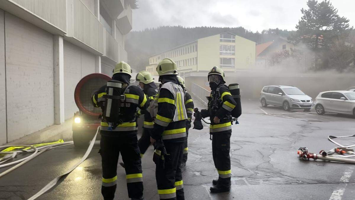 Die Feuerwehrleute stehen mit Atemschutzgeräten im Einsatz