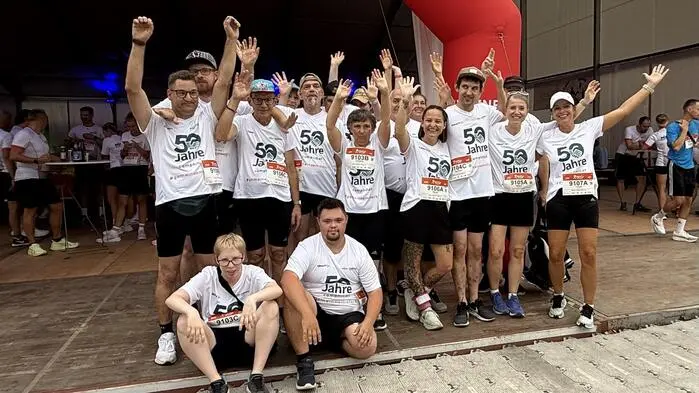 Mehrere Menschen in Sportbekleidung lächeln und jubeln in die Kamera.