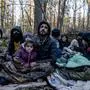 TOPSHOT - Members of a Kurdish family from Dohuk in Iraq are seen in a forest near the Polish-Belarus border while waiting for the border guard patrol, near Narewka, Poland, on November 9, 2021. - The three-generation family of 16 members with seven minors, including the youngest who is 5 months old, spent about 20 days in the forest and was pushed back to Belarus 8 times. They claim they were beaten and frightened with dogs by Belarusian soldiers. (Photo by Wojtek RADWANSKI / AFP)