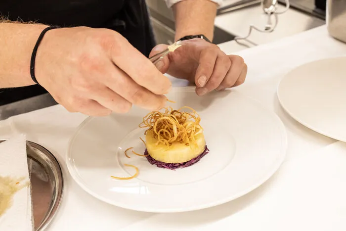 Der geschmorte Sellerie wird mit knusprigen Zwiebelringen garniert