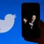 In this photo illustration, a phone screen displays a photo of Elon Musk with the Twitter logo shown in the background, on October 4, 2022, in Washington, DC. - Elon Musk has offered to push through with his buyout of Twitter at the original agreed price, reports said Tuesday, prompting a surge in the share price of the social network that triggered a suspension of trading. (Photo by OLIVIER DOULIERY / AFP)