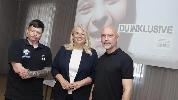 Die drei Personen vor einer Leinwand, auf die ein Bild der neuen Kampagne „Du inklusive“ projiziert wird