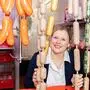 Ein lachendes Frauengesicht zwischen Wurstwaren | Daniela Hartl ist gelernte Köchin, Einzelhandelsfrau und Fleischerin mit Meisterprüfung