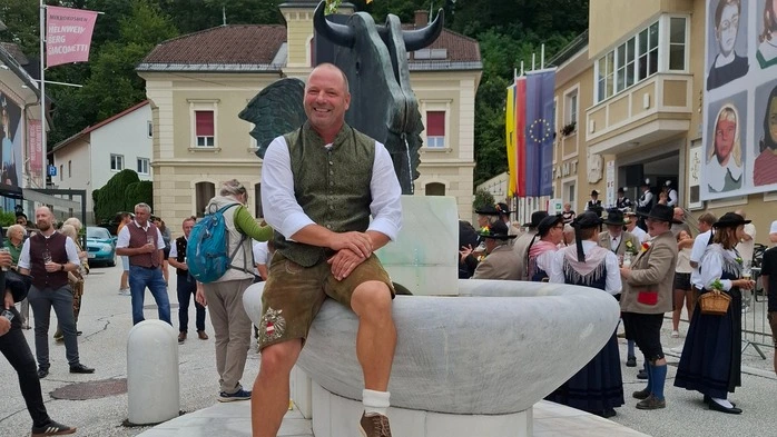 Am Bild sitzt ein Mann auf einem Brunnen 