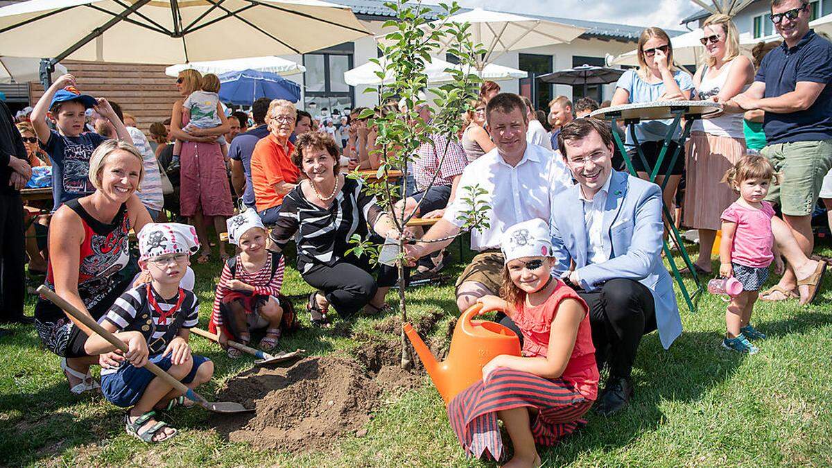 KIGA-Leiterin Martina Grubbauer, Landesrätin Ursula Lackner, Vizebürgermeister Gerald Lenger und Bürgermeister Stefan Hofer mit den Kindern beim Pflanzen des Apfelbaumes (v.l.)