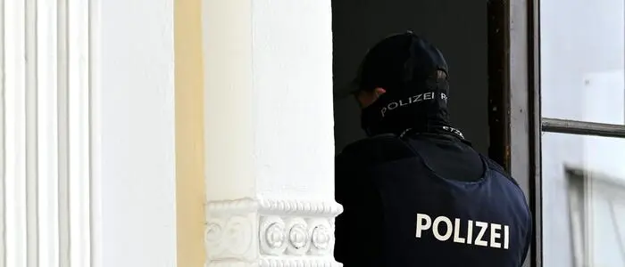Polizist von hinten, während er gerade durch eine Haustür geht | Die Polizei stellte bei der Hausdurchsuchung mehrere Beweisgegenstände sicher (Symbolfoto)