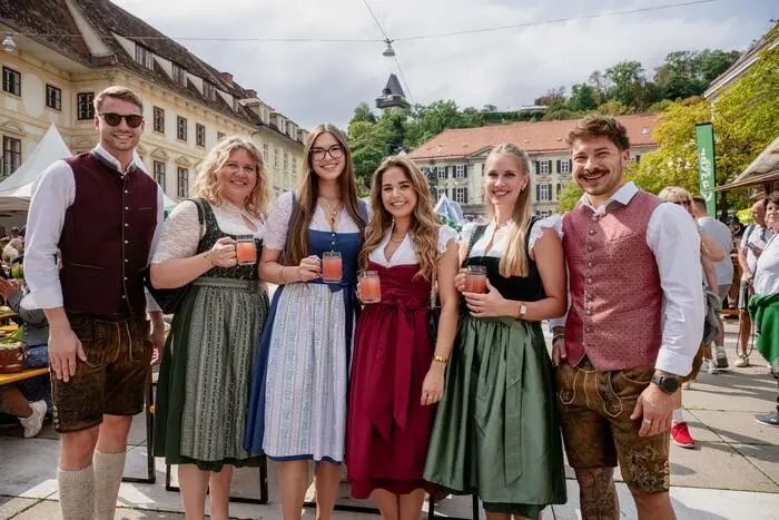 Vier junge Frauen und zwei junge Männer lächeln in die Kamera