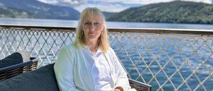 Eine Frau sitzt in einem gepolsterten Sessel am Millstätter See