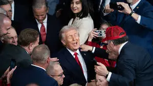 Donald Trump steht inmitten einer dichten Menschenmenge. Mehrere Personen umringen ihn, einige machen Fotos mit ihren Smartphones, während andere ihm die Hand reichen oder ihn berühren. | Trump beschwört „goldenes Zeitalter“