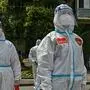 Workers and volunteers look on in a compound where residents are tested for the Covid-19 coronavirus during the second stage of a pandemic lockdown in Jing' an district in Shanghai on April 1, 2022. (Photo by Hector RETAMAL / AFP)