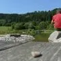 Ein Mann sitzt auf einem Stein und blickt auf einen See