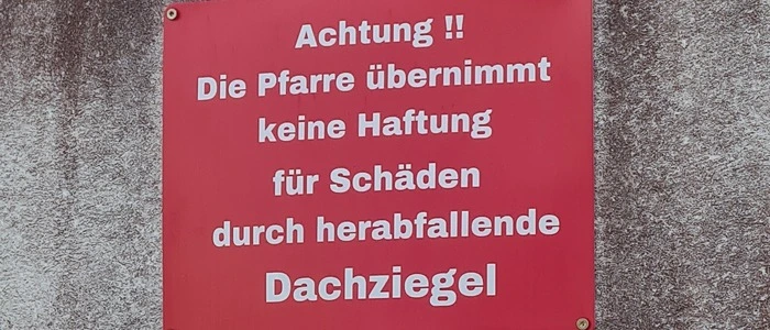 Rote Tafel mit Aufschrift hängt an einer Mauer