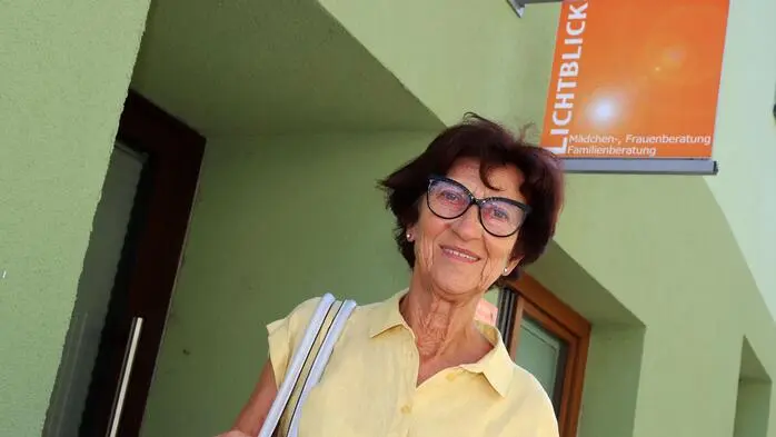 Eine ältere Dame steht vor einem grünen Gebäude