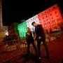 A couple, wearing face masks, walks in front of the Palazzo Chigi Government office in Rome, lit with the color of the Italian flag on November 1, 2020. - Italy reported 31,758 new cases of the virus on October 31, 2020, a new daily record. 
The government is eyeing a lockdown of the country's major cities, news media reported, to try to slow the alarming rise in infections. (Photo by Filippo MONTEFORTE / AFP)