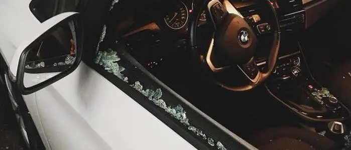 Das Bild zeigt ein weißes Auto mit einer eingeschlagenen Scheibe auf der Fahrerseite