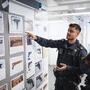 Ein Polizist und eine Polizistin inspizieren Fotos beschlagnahmter Waffen im Wachzimmer in Rinkeby 