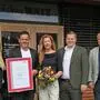Das Bild zeigt fünf Menschen vor einer Firma. Michael Watz hält eine Urkunde anlässlich des Jubiläums in der Hand, daneben steht seine Frau Petra Watz mit einem Blumenstrauß. Es gratulieren Claudia Brabec und Martin Heidinger, WKO, und Alfred Lenz, Bürgermeister von Heimschuh | Claudia Brabec, WKO, Michael und Petra Watz sowie Martin Heidinger, WKO, und Alfred Lenz, Bürgermeister von Heimschuh (v. l.)