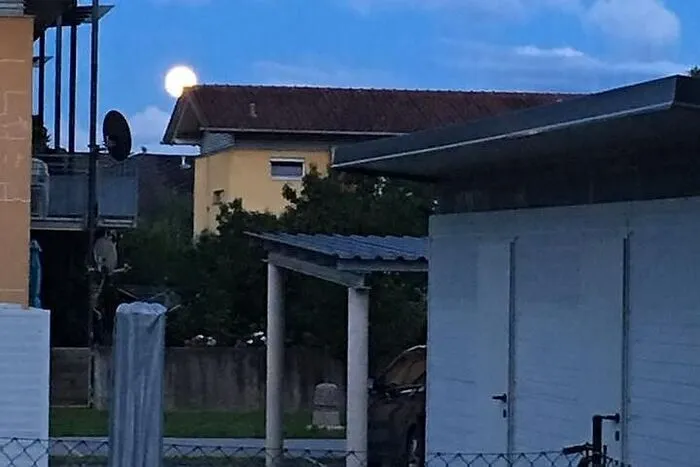 Hier lugt der Erdbeermond hinter einem Haus hervor.