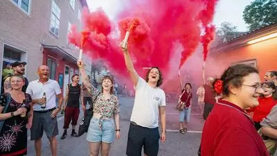 Menschen feiern Wahlerfolg der KPÖ Graz mit roter Pyrotechnik