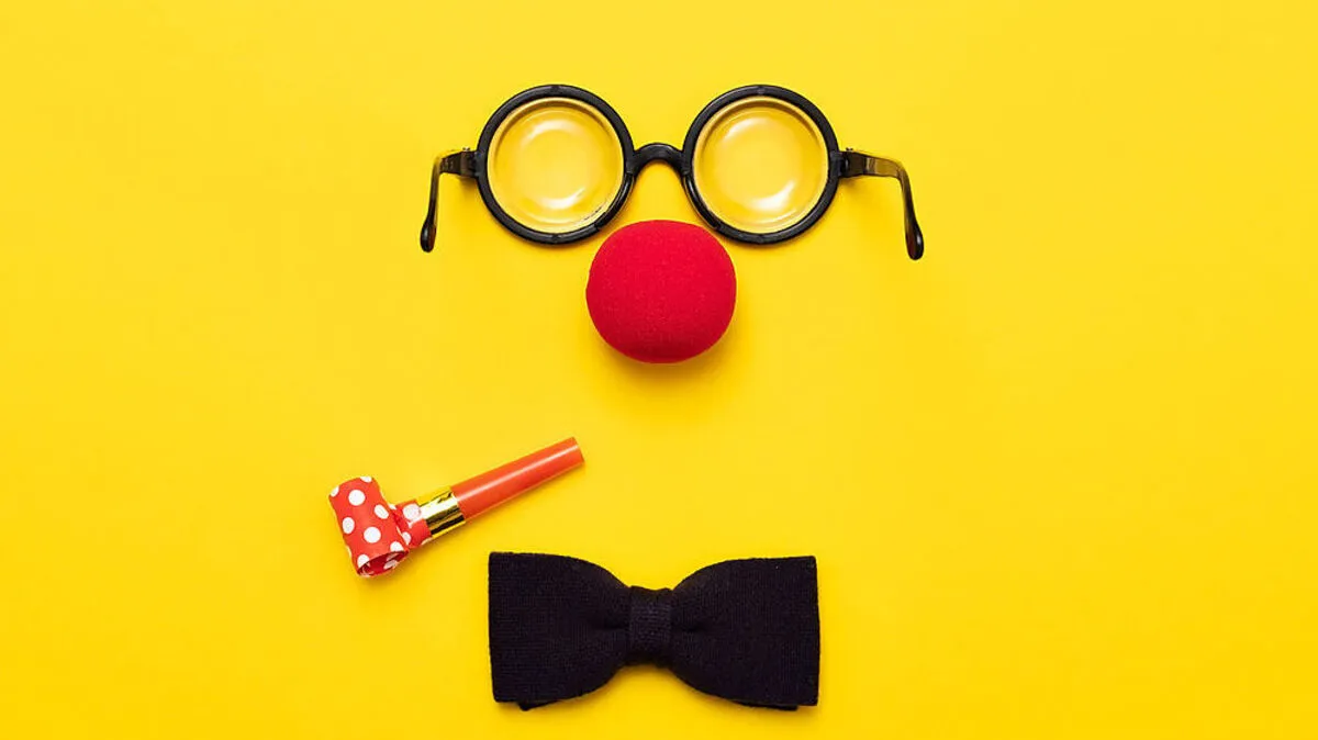 Funny glasses, red clown nose and tie lie on a colored background, like a face.