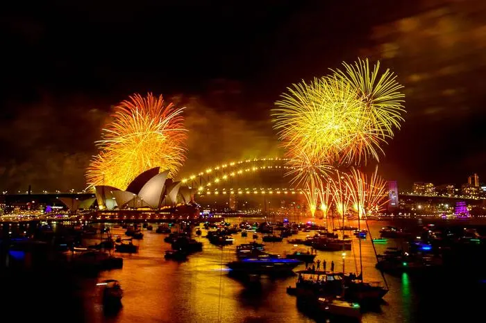 Fireworks explode over the Sydney Harbour Bridge and Sydney Opera House (L) during New Year's Eve celebrations in Sydney on January 1, 2024. (Photo by Izhar KHAN / AFP)
