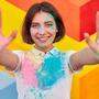 Happy woman with colorful face and clothes showing hands