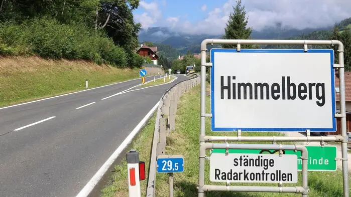 Foto einer Ortseinfahrt mit Ortstafel im Sommer.