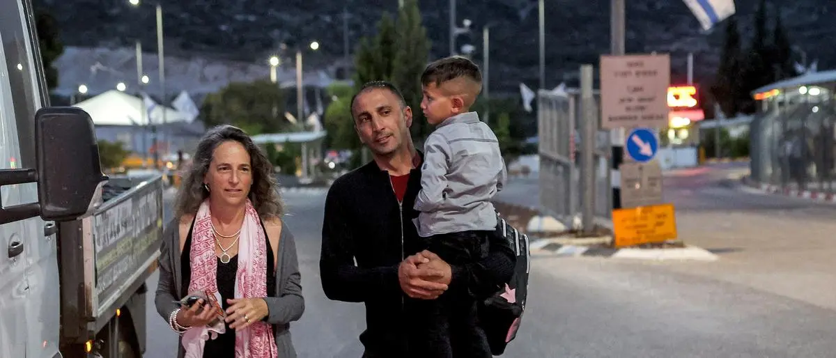 Adam Abu al-Rob, a six-year-old Palestinian eye cancer patient, is carried by his father Mamoun as they meet with Israeli NGO volunteer Yael Noy at the Rehan checkpoint between Israel and the occupied West Bank, driven by her on their way from the Palestinian village of Jalbun to Shiba Hospital Tel Hashomer near Tel Aviv, on May 22, 2023. The Palestinian Authority pays for the treatments of Palestinian patients from the West Bank like Abu al-Rob, but does not cover transportation to and from hospitals, the cost of which can be prohibitive for many families. Israeli group Road to Recovery, which was established in 2010 and boasts some 1,000 active members, takes dozens of Palestinians daily -- mostly children -- from West Bank and Gaza crossing points to Israeli hospitals for treatment unavailable in the Palestinian territories. (Photo by JACK GUEZ / AFP)