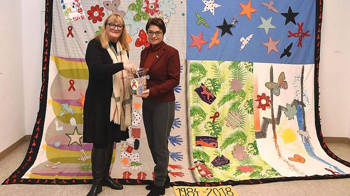 Michaela Wilhelmer und Beate Prettner vor dem „Memorial Quilt“, der an jene 166 Menschen erinnert, die in den letzten 35 Jahren in Kärnten an Aids verstorben sind