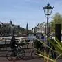 Men ride bikes as a boat cruises along a canal in Amsterdam, on April 12, 2024. (Photo by JOHN THYS / AFP)