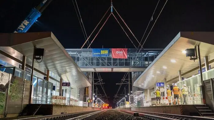 ÖBB-Bahnhof: Die Bahnsteige links und rechts mit dem neuen Personensteg darüber, im Hintergrund noch der Kran und die Seile zu sehen