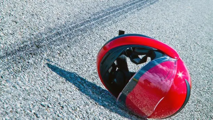 Ein roter Motorradhelm liegt auf einer Straße